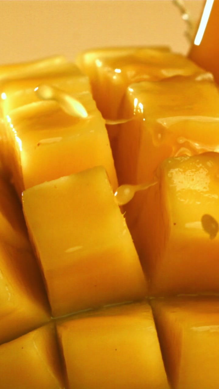 Sciroppo dorato dolce che si versa su cubetti di mango fresco