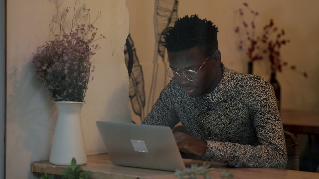 Concentrated young man working with laptop in cafe