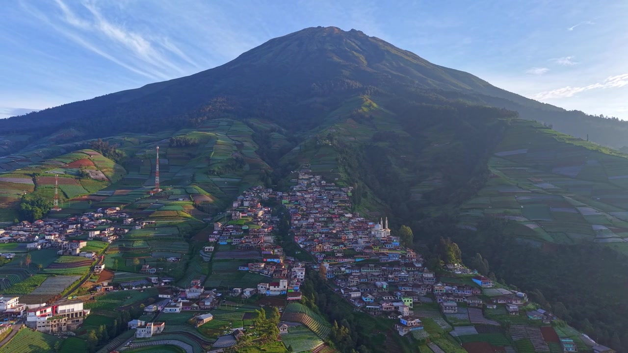 Filmato da drone di un villaggio rurale su un pendio di montagna con lussureggianti campi agricoli e imponenti scenari vulcanici. Perfetta destinazione di viaggio nella natura nel Sud-est asiatico. Nepal Van Java, Indonesia