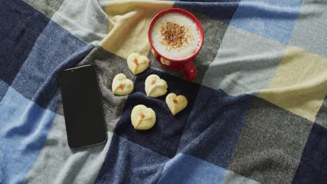 Video-Von-Kaffee,-Keksen-Und-Smartphone,-Die-Auf-Einer-Karierten-Decke-Liegen