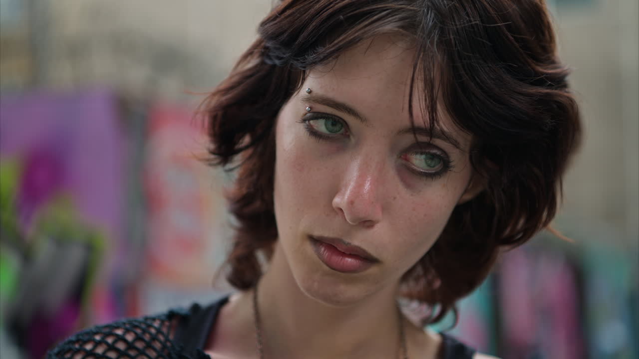 портрет молодой женщины в альтернативном стиле с пирсингом бровей перед граффити покрытой стеной на улице лондон сити в великобритании в режиме реального времени 2