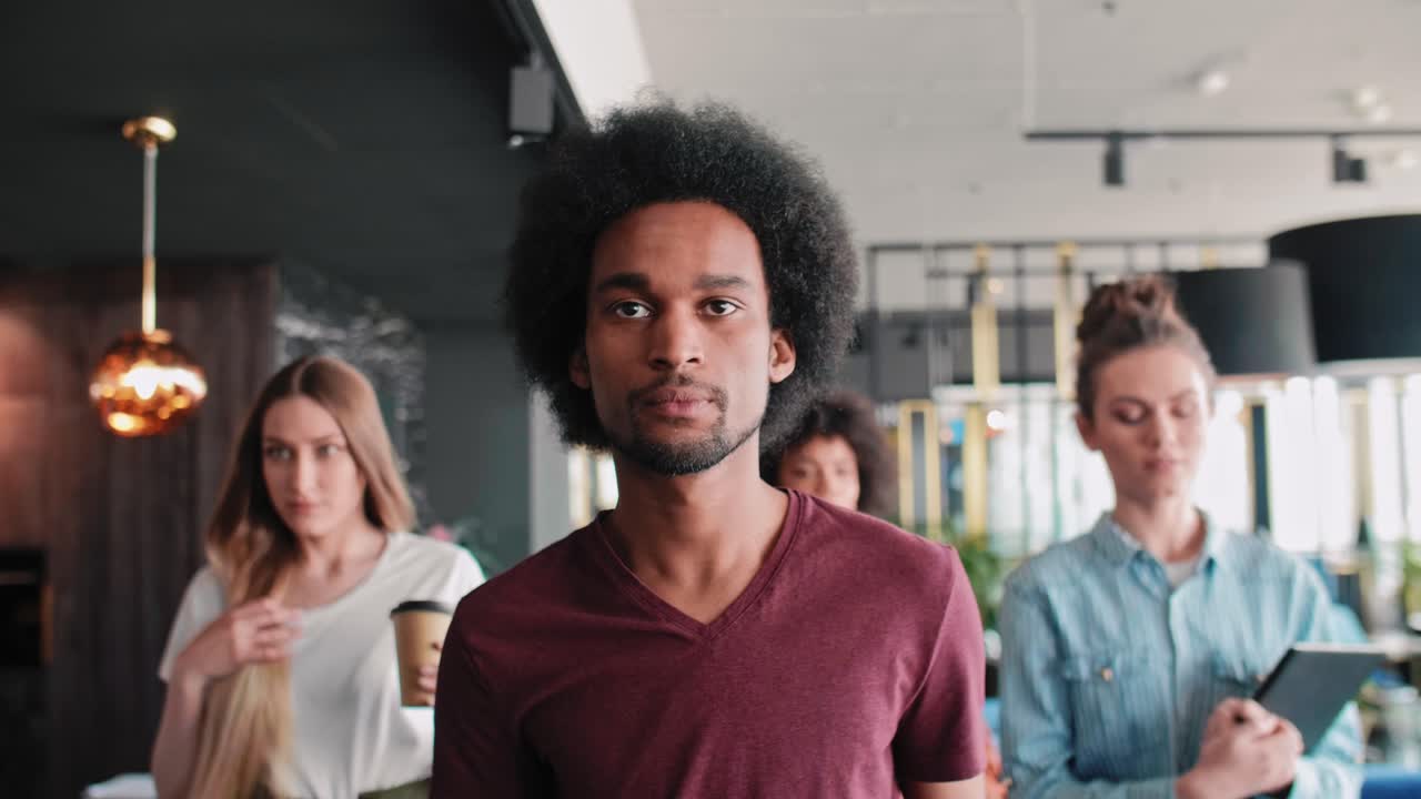 Determined African man and his coworkers walking in the corridor