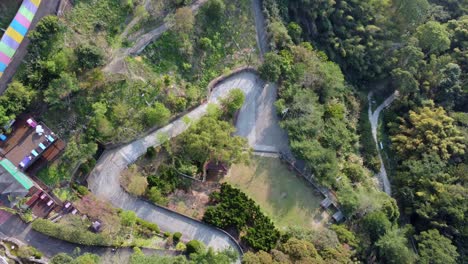 Eine-Kurvenreiche-Straße-Durch-üppiges-Grün-In-Einer-Ruhigen-Parkähnlichen-Umgebung,-Möglicherweise-Im-Morgengrauen,-Luftaufnahme