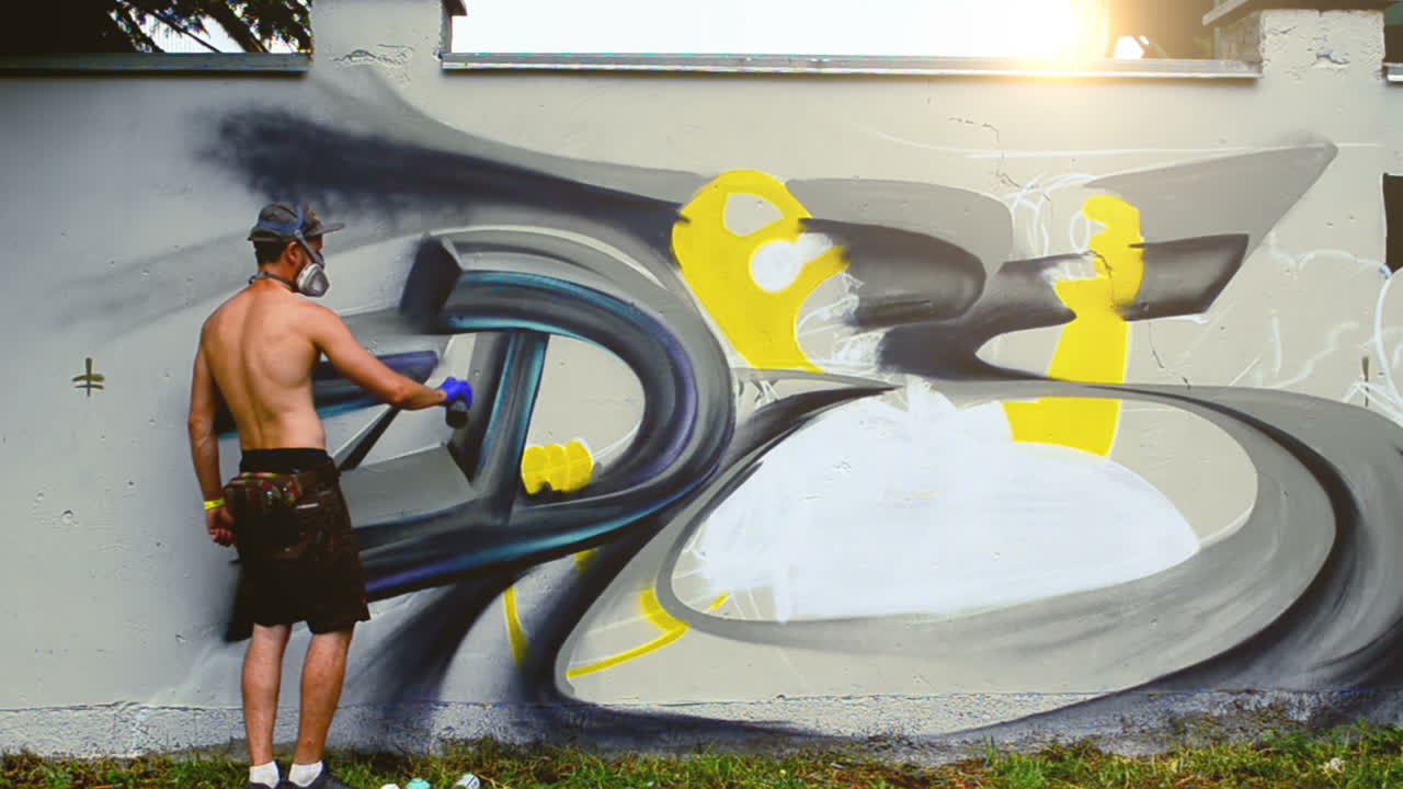 Sanatçı bir çit üzerine grafiti çiziyor. Çit üzerinde grafiti