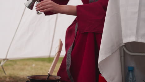 female mag pours magic potion into small glass bottle