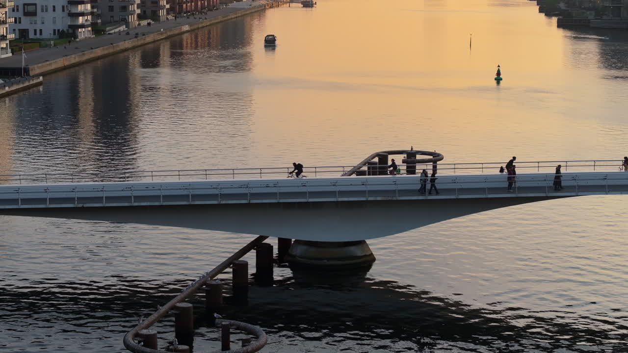 Aerial drone view of people moving on the Quay Bridge across the port of Copenhagen, Denmark in the evening