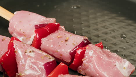raw pork and red bell pepper skewers ready to cook