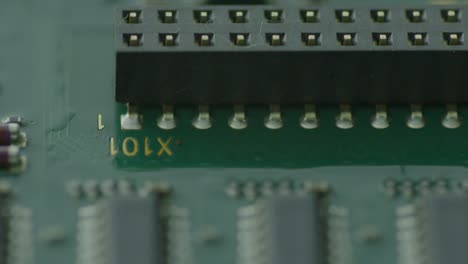 the image reveals a close-up view of a green circuit board teeming with various electronic components, with a conspicuous circular hole featuring a gold interior taking center stage