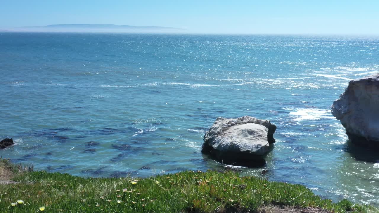 прогулка вдоль обрыва с видом на океан, затем панорамирование для просмотра огромной скалы вдоль берега