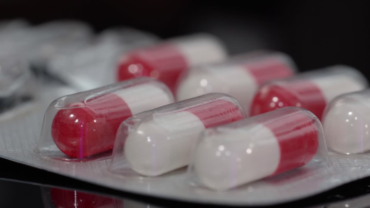 Close up of red and white medicine capsules inside blister pack, pharmaceutical product shot