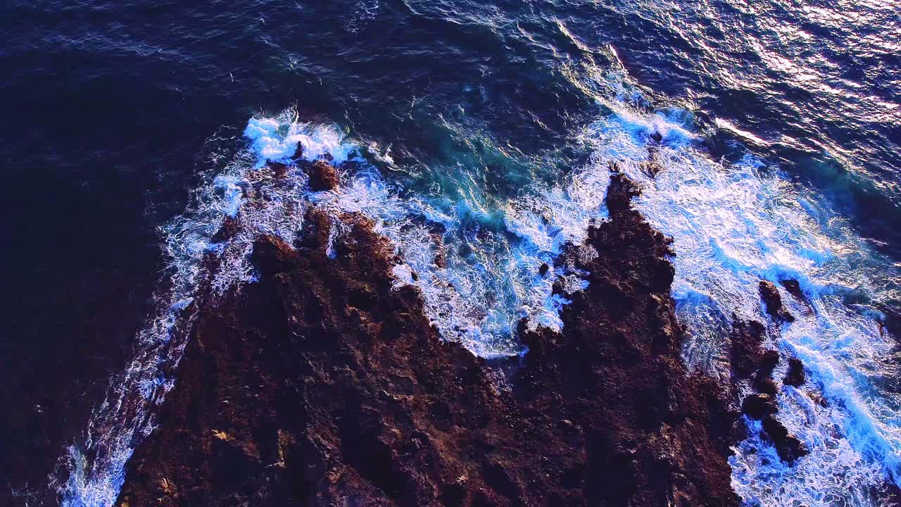 fotografía cenital de pequeñas olas que salpican suavemente las rocas en los cristianos, tenerife