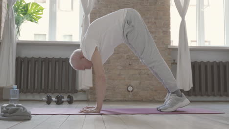 old male stretching and exercising on yoga mat at home