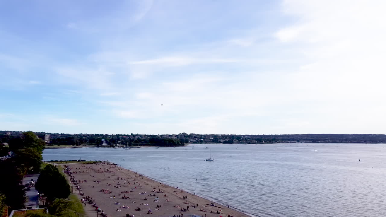 Aerial panout of Sunset Beach English Bay harbor where mass crowds of people respectfully social physical distancing each other at the hottest summer hang out area in Vancouver Canada West Coast
