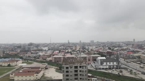 Ascending-above-a-construction-site,-a-drone-observes-the-dynamic-activity,-gradually-revealing-the-vibrant-cityscape-of-Lekki,-Lagos,-Nigeria,-capturing-the-synergy-of-urban-development