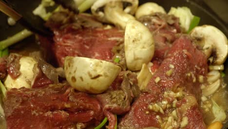 preparación de comida coreana - persona volteando carne en una olla - primer plano