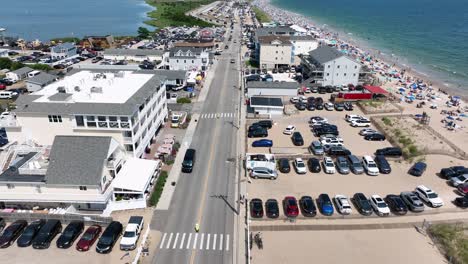 busy parking area at sandy beach of misquamicut, rhode island. aerial flyover shot. blue seascape and many people at beach. flyover shot. sunny summer day with blue sky