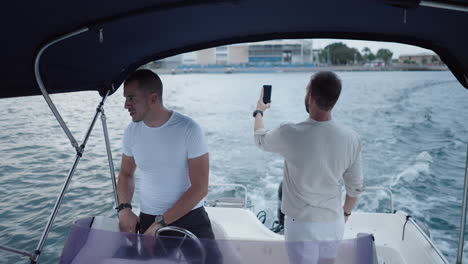 two friends enjoying a boat trip and filming with a smartphone