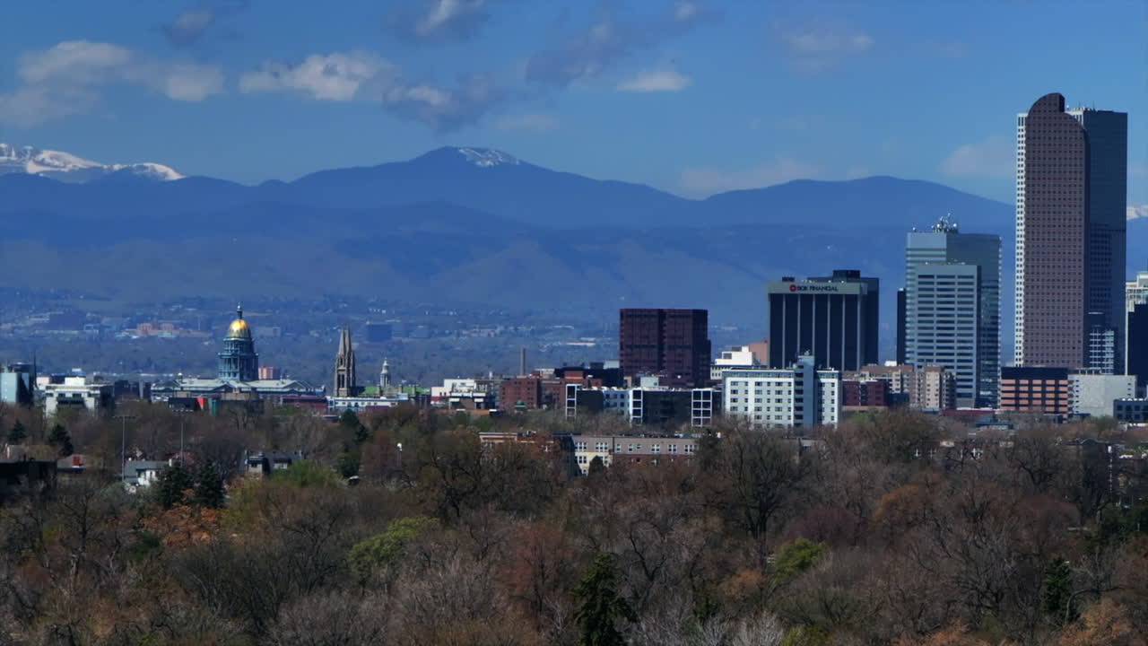 Colorado State Capitol City Park Historic building Downtown Denver Colorado aerial drone springtime summer sunny morning blue sky tall buildings skyscrapers city scape mountains pan right motion