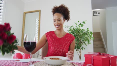 Happy-mixed-race-woman-on-a-valentines-date-video-call,-holding-flowers