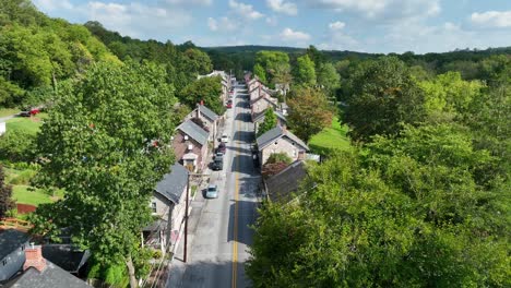 Narrow-street-with-stone-houses-and-green-trees-in-summer