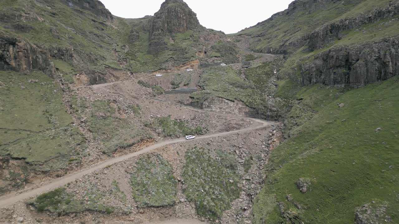 los vehículos deportivos utilitarios blancos suben las empinadas curvas de grava del sani pass hacia lesotho