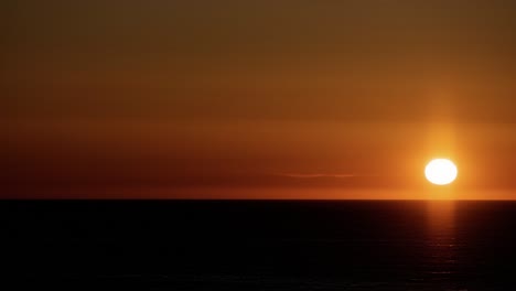 the midnight sun in its early stage. close up time lapse. the sun moves horizontally over the sea; enters the scene from the left and exits on the right. lofoten islands, northern norway