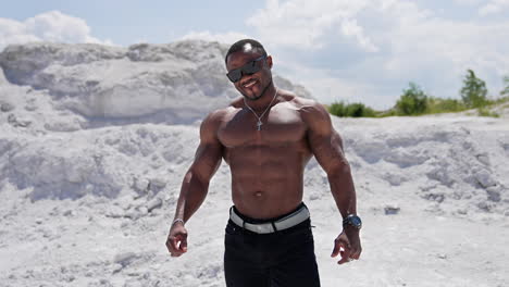 full length view of the strong muscle man walking outdoor with naked torso. shirtless guy on a background of sandy landscapes