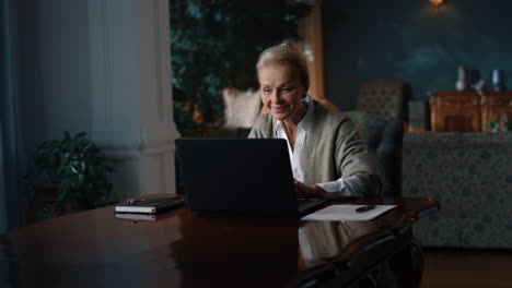 smiling old woman reading good news on laptop computer at home