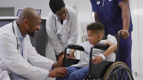 diverse doctors talking to child patient sitting in wheelchair at hospital