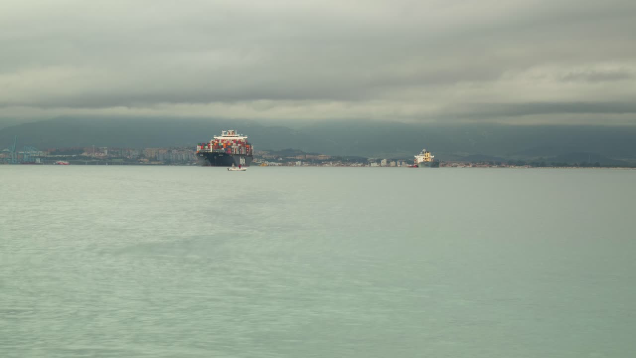 buque de contenedores atracado cerca del puerto de gibraltar, vista en lapso de tiempo con nubes tormentosas