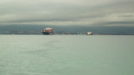 container vessel moored near gibraltar harbor, time lapse view with stormy clouds