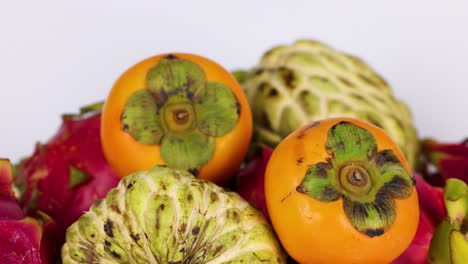 vibrant display of persimmons, dragon fruit, cherimoya