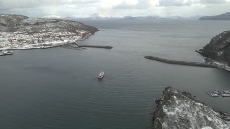 Boat-leaves-Skjervoy-harbor-heading-towards-fishing-grounds-in-the-Arctic,-drone