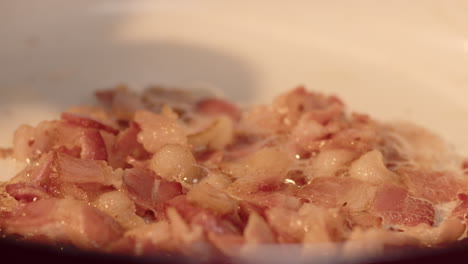 bacon fat lard being rendered in a pan with a spoon