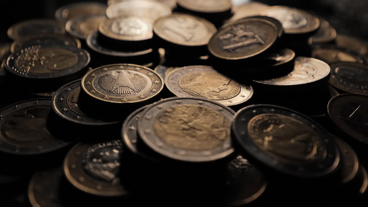 Stack of euro coins in shadowed light, highlighting metallic details and value