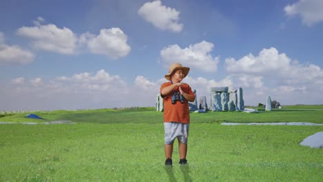 Asian Boy With A Hat And Binoculars Shaking Head Showing Time Out Gesture While Traveling In Stonehenge. Boy Researcher, Travel Tourism Adventure Concept, Full Body