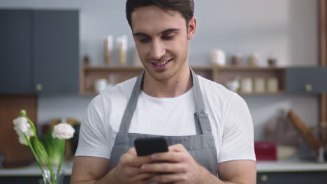 Man-cook-looking-recipe-on-mobile-phone-at-home-kitchen.-Chef-planning-new-dish