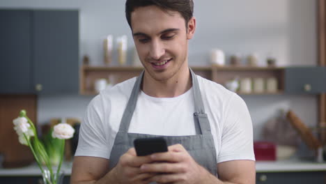 hombre cocinero buscando receta en el teléfono móvil en la cocina de casa. chef planeando un nuevo plato