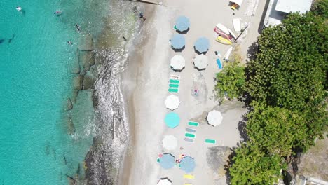 Playa-piskado-in-curacao-with-umbrellas-and-clear-blue-waters,-aerial-view