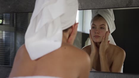 Caucasian-woman-looking-in-mirror-after-shower-in-hotel