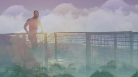 Animation-of-clouds-over-african-american-man-running-at-beach