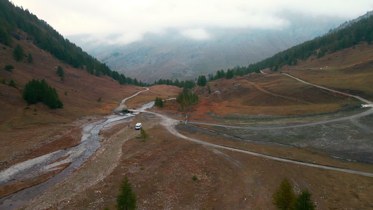 turistas con camionetas estacionadas cerca del arroyo en el valle al atardecer, preparando fogatas durante el otoño en valle argentera, piamonte, italia