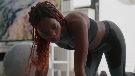 athlete woman with black skin doing running plank exercise on yoga map