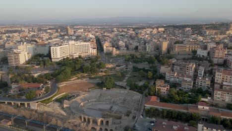 A-cinematic-slow-drone-approach-to-the-morning-cityscape-of-Tarragona,-Spain,-featuring-the-iconic-Roman-coliseum-and-the-city's-grand-cathedral