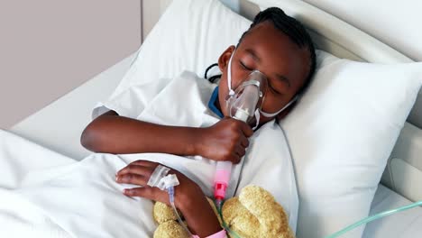 sick girl in oxygen mask resting with teddy bear