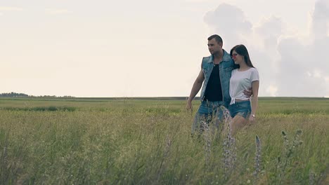 girl in orange sunglasses walks on yellow field with man