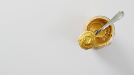 Video-of-close-up-of-jar-of-peanut-butter-on-white-background