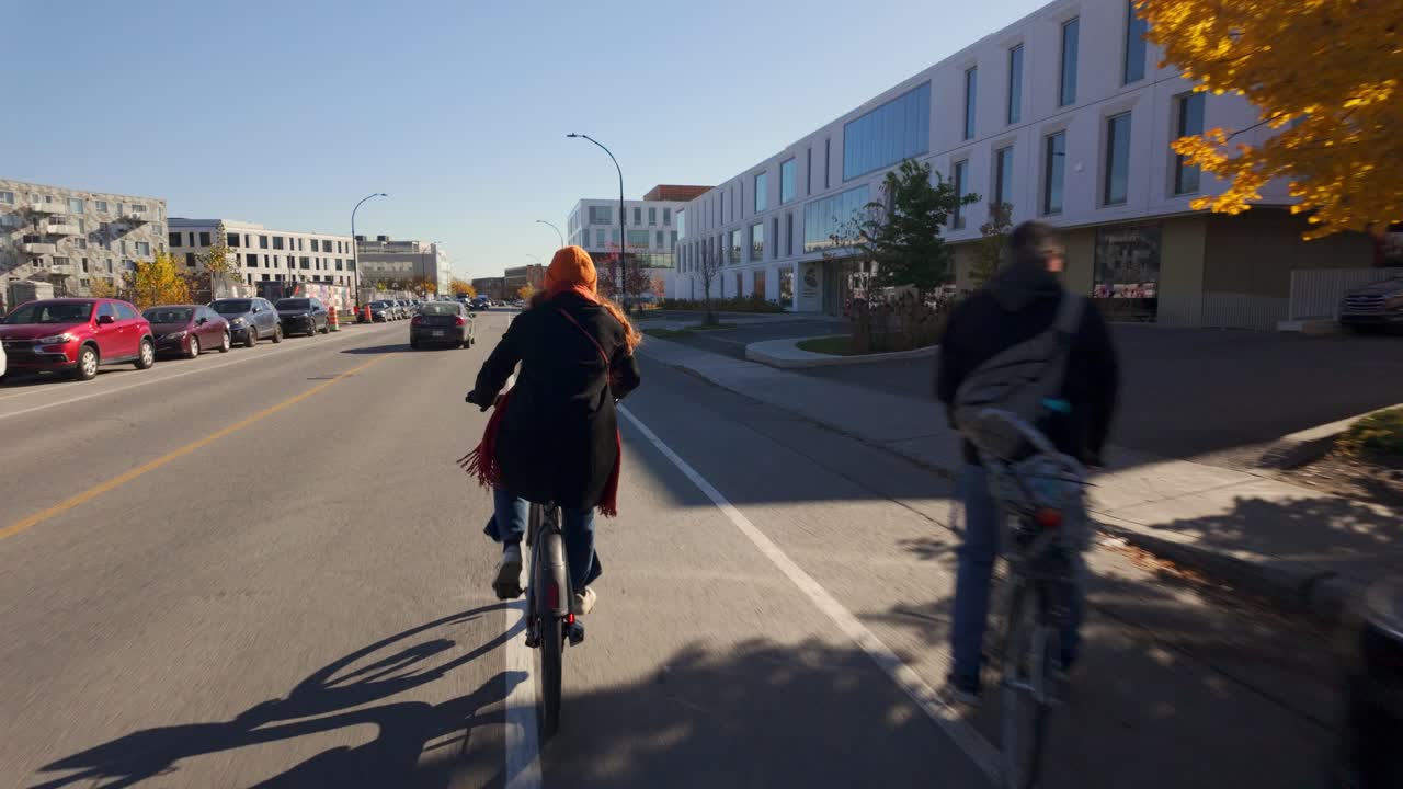 Woman Cycling on City Street in Autumn