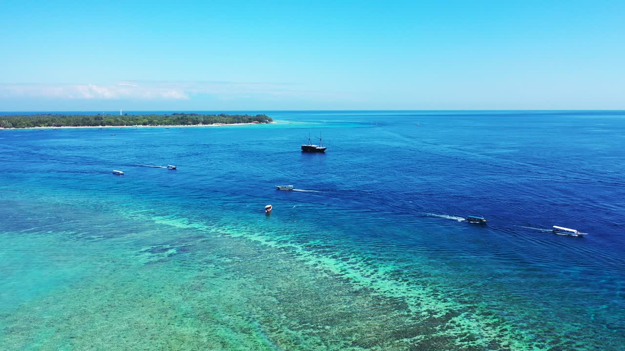 Colori vividi della vista panoramica di barche che navigano sul mare blu profondo e una laguna turchese con barriere coralline sulla costa di isole tropicali a Bali