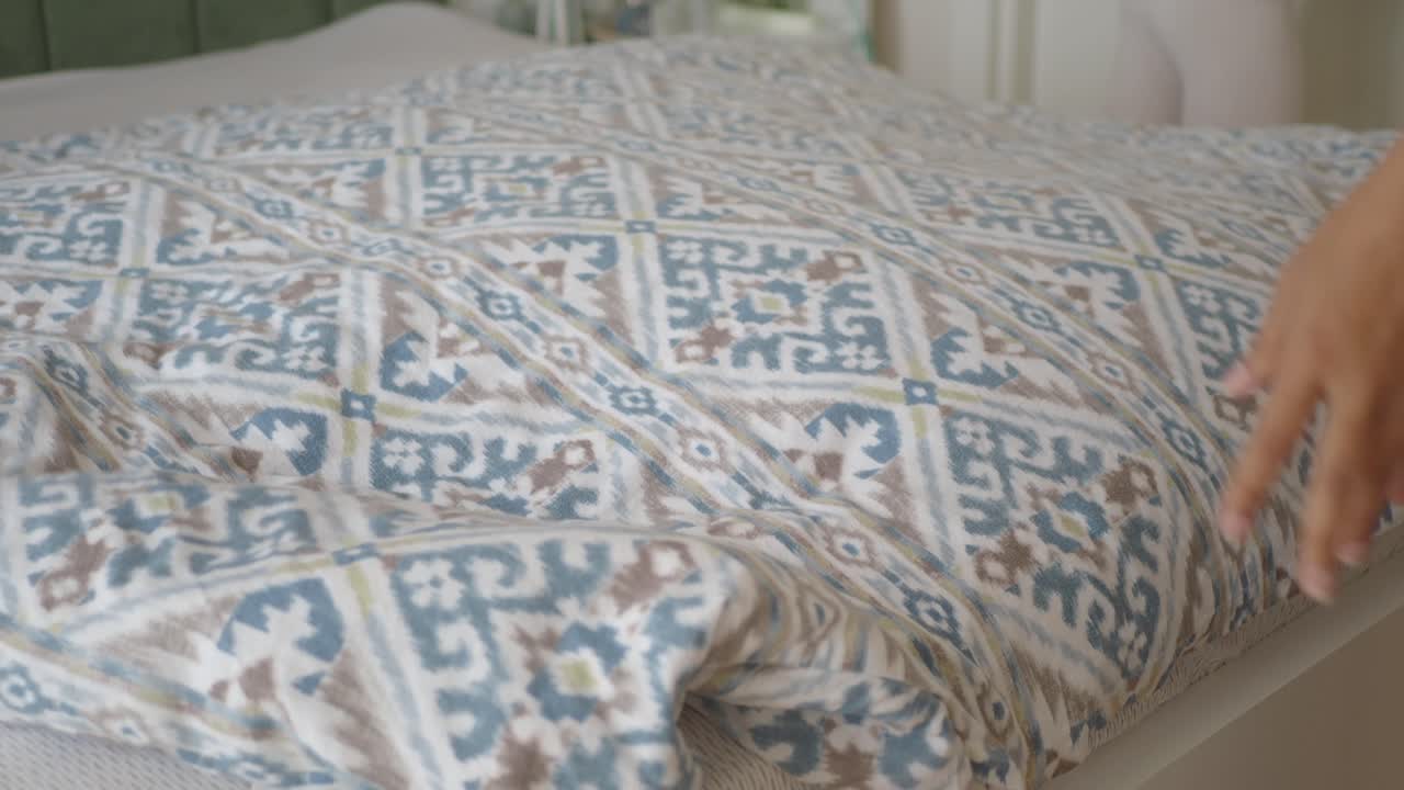Persona che sistema un copripiumino fantasia su un letto